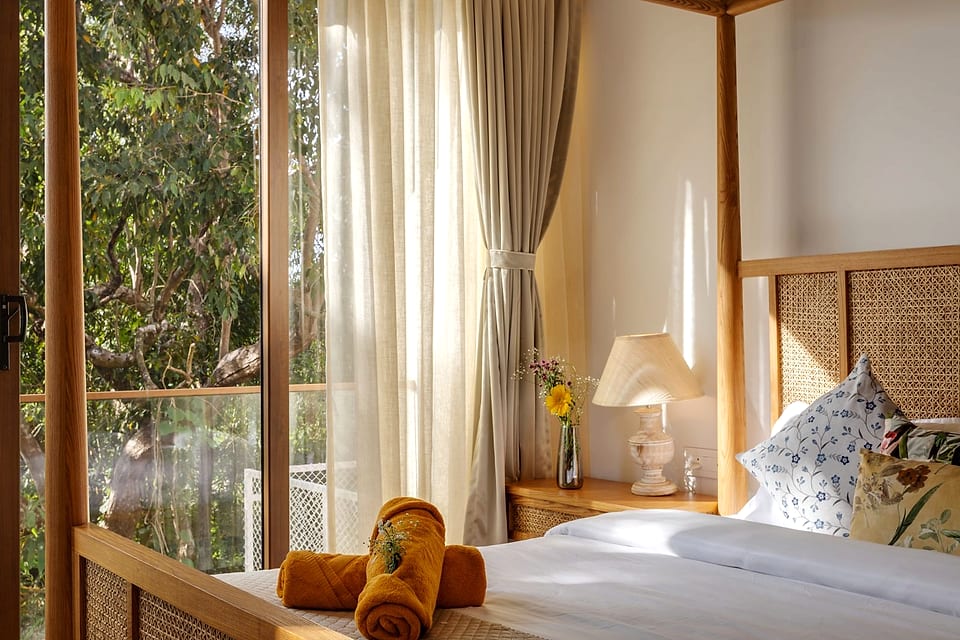 Casa Keval, bed dressed with bolsters beside the garden window